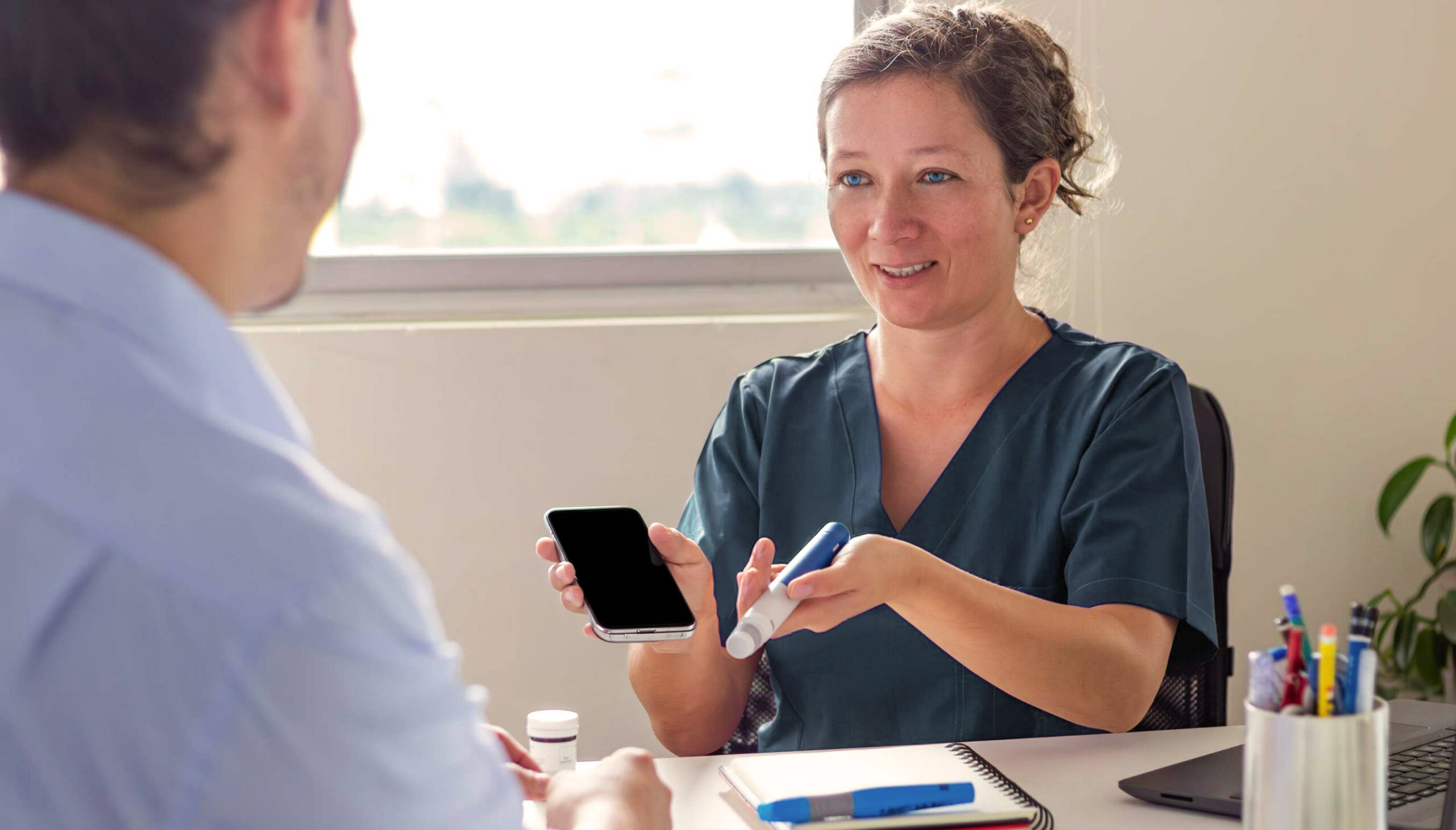 provider showing patient an autoinjector and digital support device